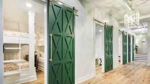 Una habitación con literas, puertas correderas verdes y una escalera.