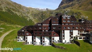 A large, multi-story building with a distinctive circular window design, set in a mountainous landscape. - Wonderful apartment inside the top residence kurz (Maso Corto)