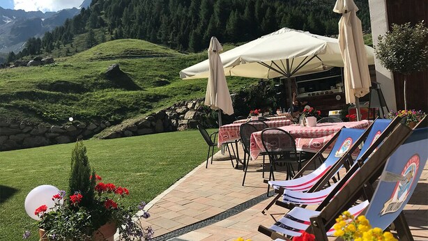 An outdoor patio with tables and chairs, umbrellas, and a view of a mountainous landscape. - Wonderful apartment inside the top residence kurz (Maso Corto)