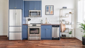 Una cocina moderna con armarios azules, electrodomésticos de acero inoxidable y suelo de madera.