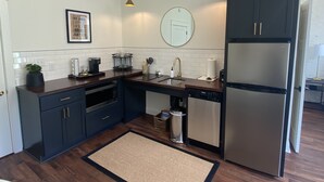 Eine moderne Küche mit dunklen Schränken, einem Edelstahlkühlschrank, einem Geschirrspüler und einer Kaffeemaschine.