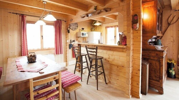 A wooden cabin interior with a dining area, bar, and kitchen. - Chalet Anais, traditional Alpine feel (Montgenevre)