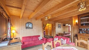 A wooden interior with a red sofa, wooden dining table, and a fireplace. - Chalet Anais, traditional Alpine feel (Montgenevre)