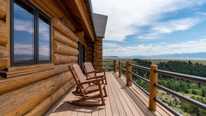 A log cabin with a deck featuring rocking chairs and a view of a mountainous landscape. - Arrowhead Lodge -Secluded home with incredible views and now Air Conditioning (Livingston)