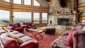 A spacious living room with large windows, a stone fireplace, and a cozy seating area. - Arrowhead Lodge -Secluded home with incredible views and now Air Conditioning (Livingston)