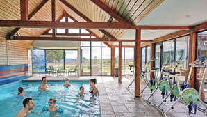 An indoor swimming pool with a covered area, exercise bikes, and a view of the outdoors. - House La Houle Erquy *Pool* *Beach at 800m* (Erquy)