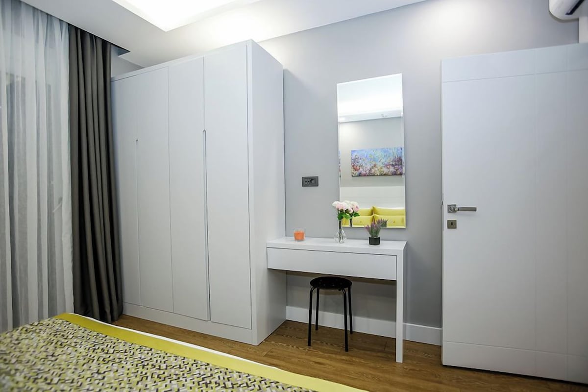 Un dormitorio con cama, escritorio, silla, armario y espejo.