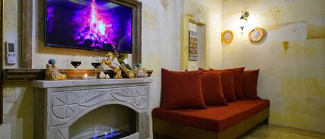 A living room with a fireplace, a television mounted above it, and a red sofa.