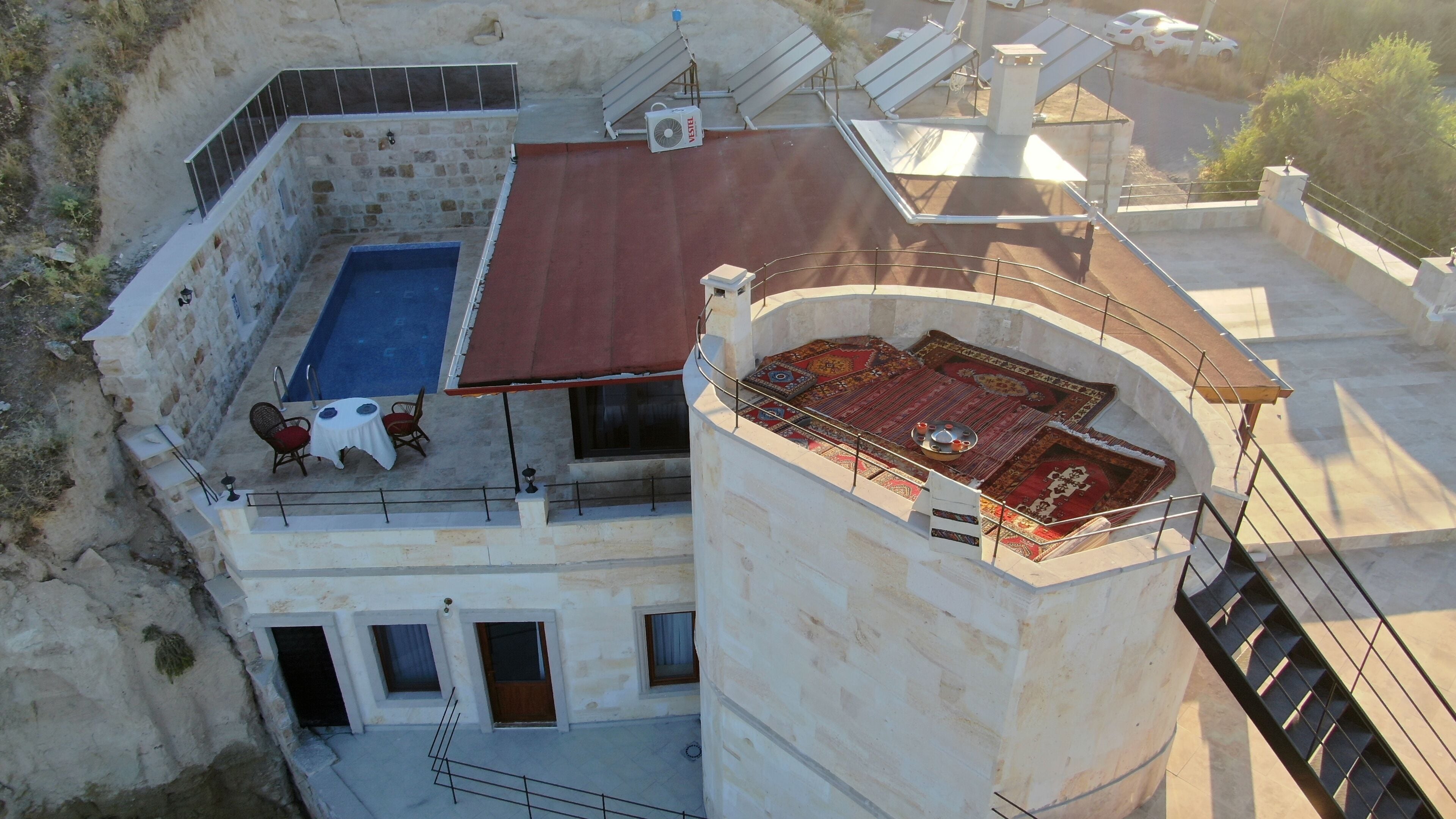 Un edificio de piedra con piscina en la azotea, terraza cubierta y vistas del paisaje circundante.
