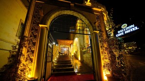 An entrance to the Balloon Cave Hotel with a red carpet, a staircase, and a signboard.
