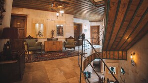 A spacious living area with a wooden staircase, a fireplace, and a large rug.