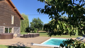 A wooden house with a pool, outdoor seating, and a garden.