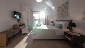 A modern hotel room with a bed, bedside table, TV, and a view of the outdoors. - Abeloessa Methonian Hospitality (Pylos-Nestoras)