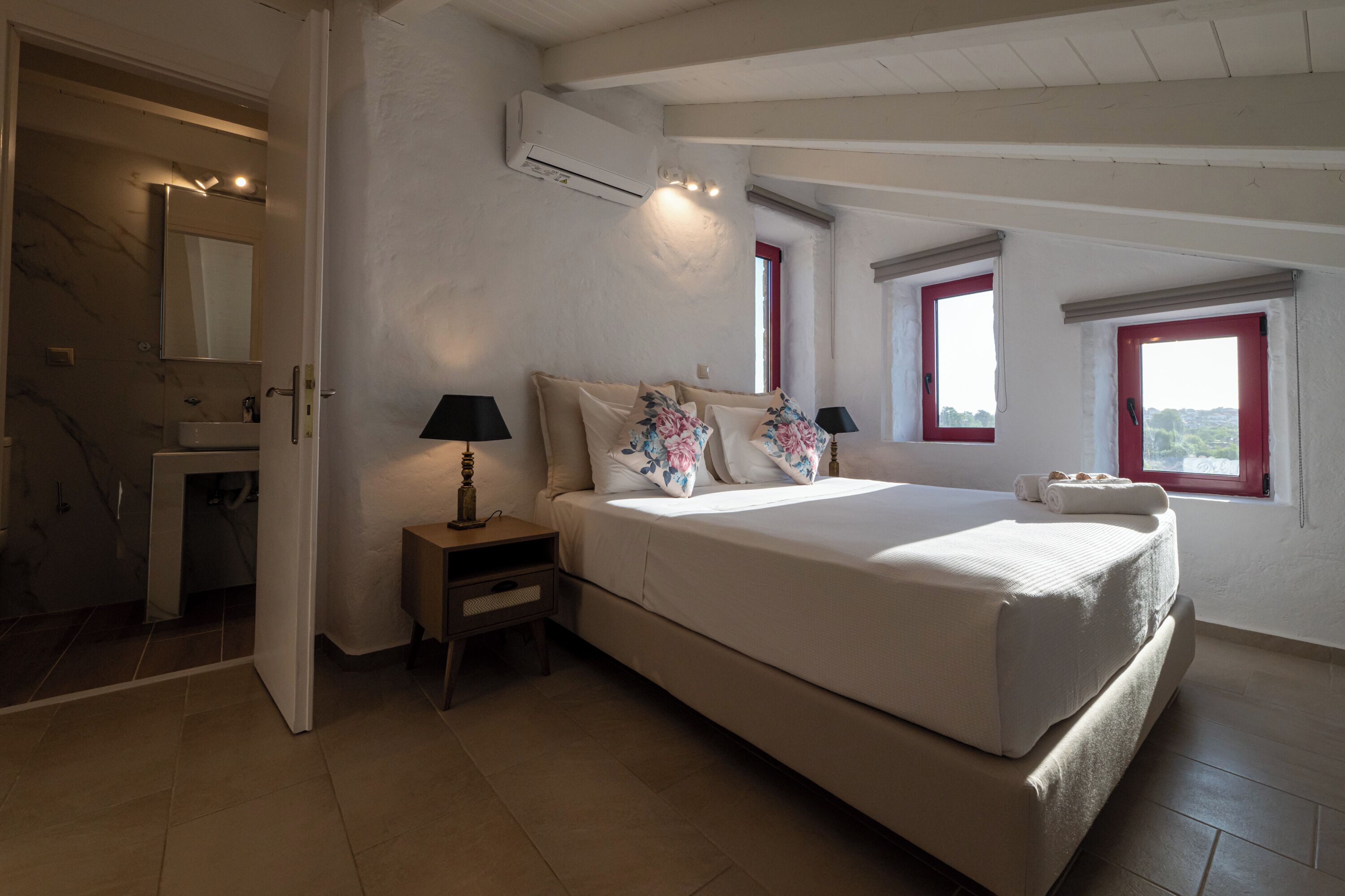 Una camera da letto con un letto, comodini, uno specchio e una finestra.
