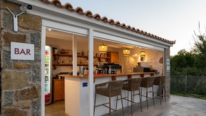 A bar with a stone wall, wooden shelves, and bar stools. - Abeloessa Methonian Hospitality (Pylos-Nestoras)