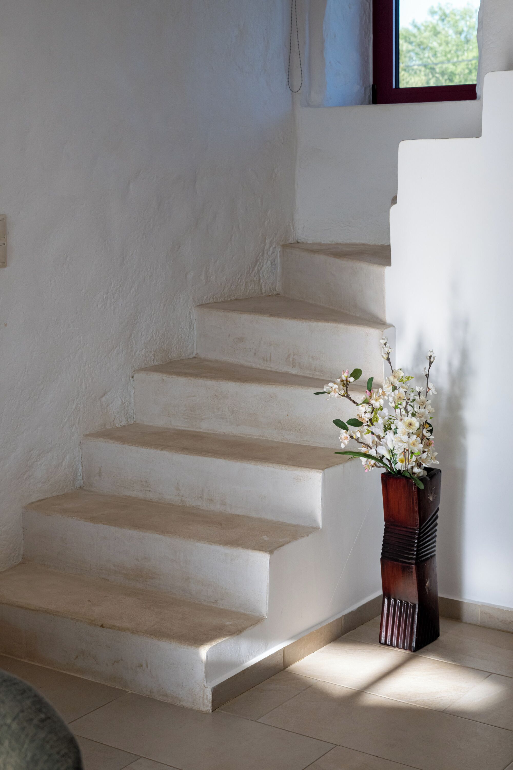 A staircase with a vase of flowers at the bottom.