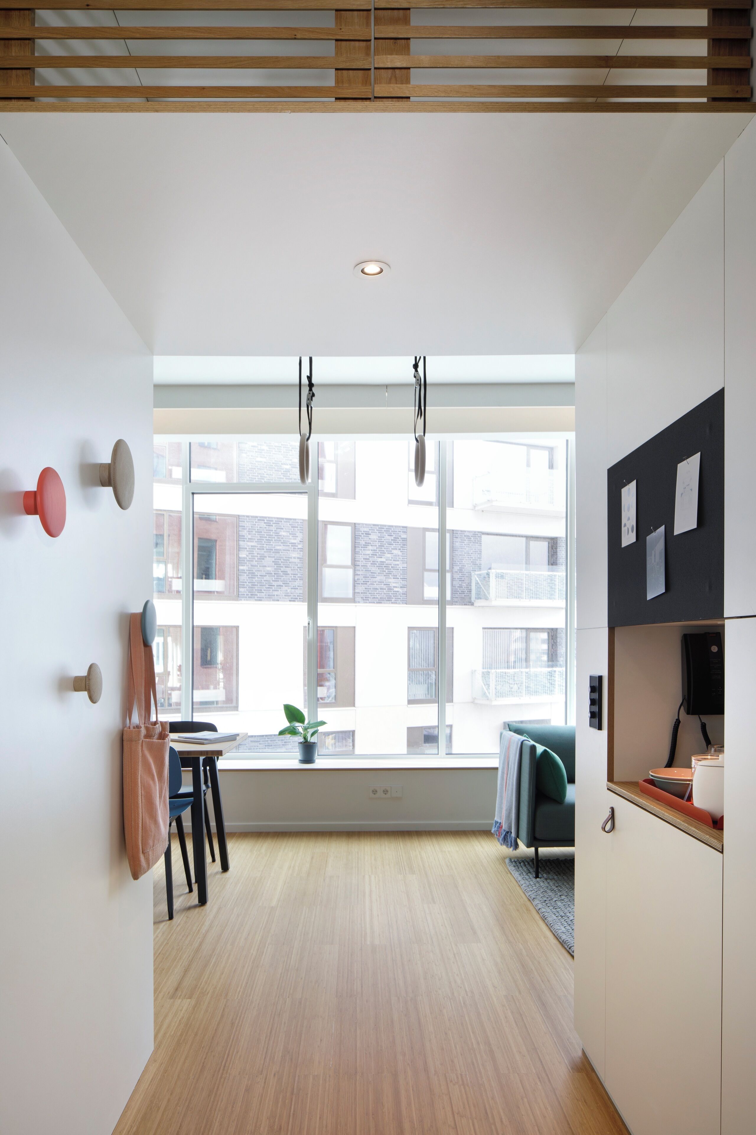 Una cocina moderna con suelo de madera, una ventana con vistas a edificios y una lámpara colgante.