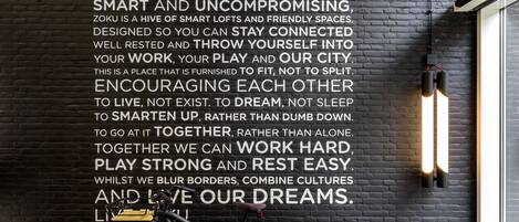 Una pared de ladrillo negro con texto motivacional y una bicicleta apoyada en ella.