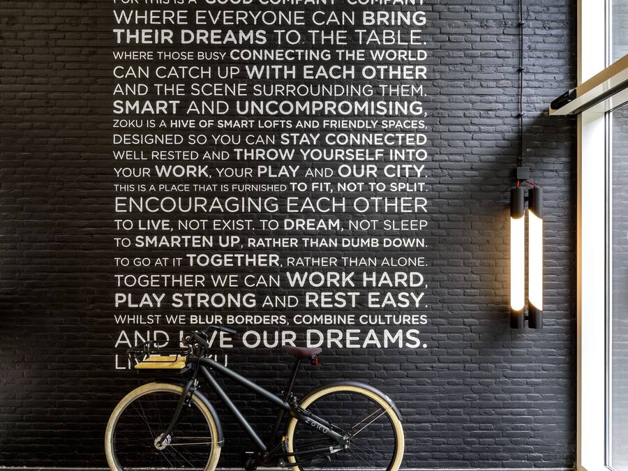 A black brick wall with motivational text and a bicycle leaning against it.