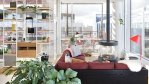 Een moderne woonkamer met een rode bank, een open haard en een groot raam met uitzicht op een stadsbeeld.