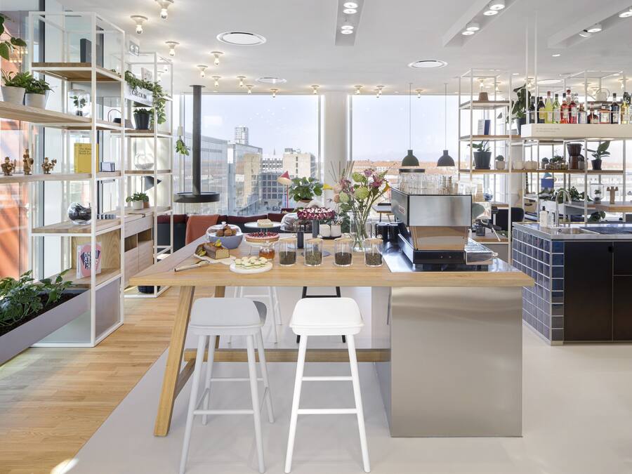 Een moderne keuken met een centraal kookeiland, barstoelen en een koffieapparaat.