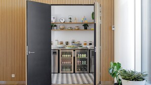 Een moderne keuken met een geruit vloertje, houten paneelwanden en diverse keukengerei en planten op planken.