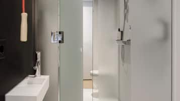 A modern bathroom with a glass partition, a white sink, and a shower area.