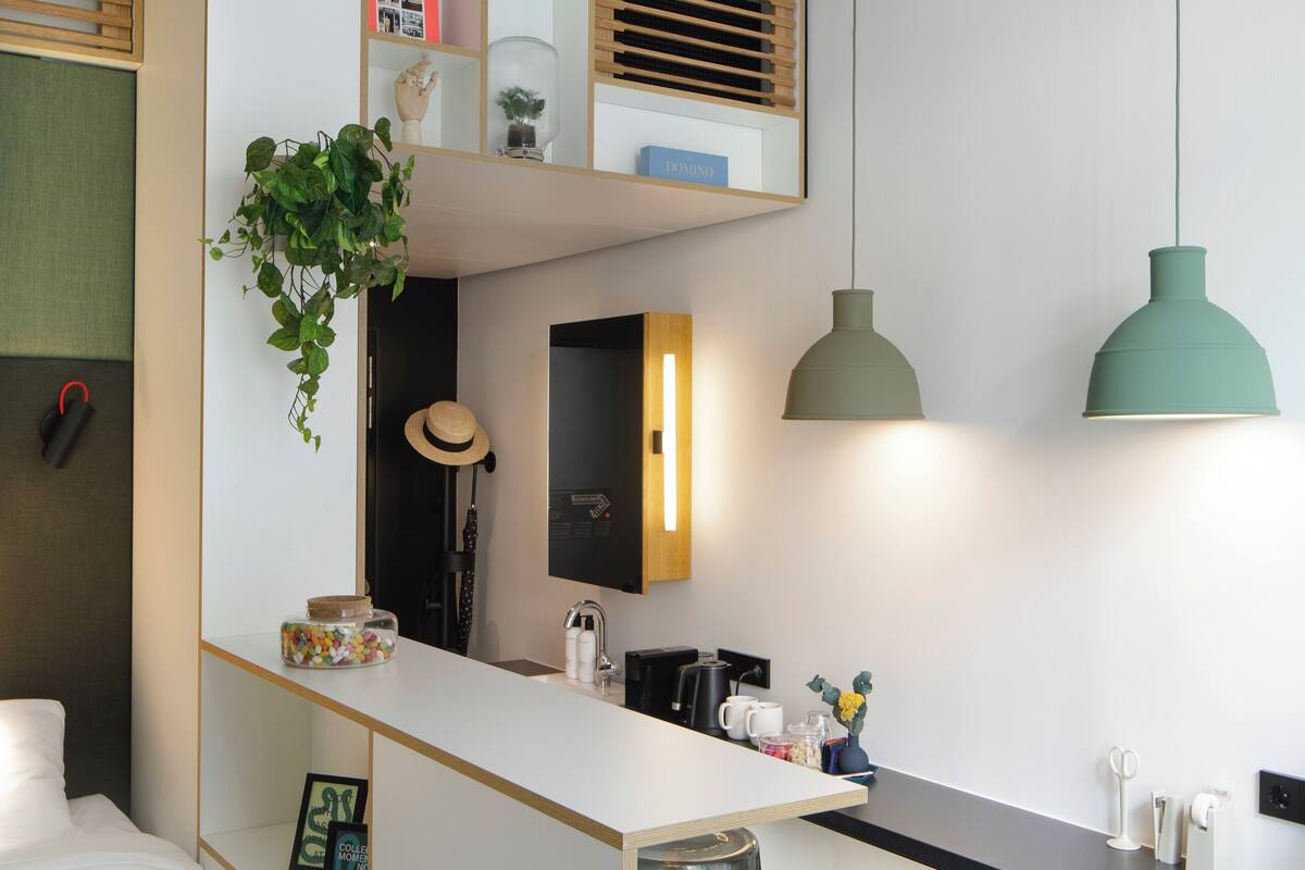 Een moderne slaapkamer met een stapelbed, een bureau en een groene kruk.
