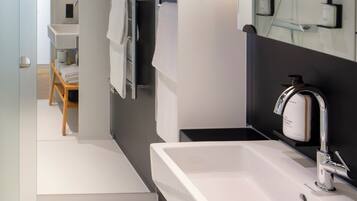 A modern bathroom with a large mirror, a sink, and a shower.