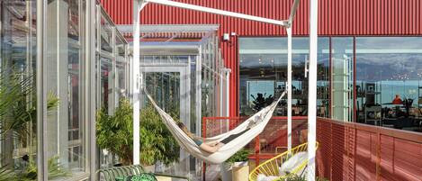 Eine moderne Außenpatio mit einer Hängematte, Sitzgelegenheiten und Topfpflanzen.