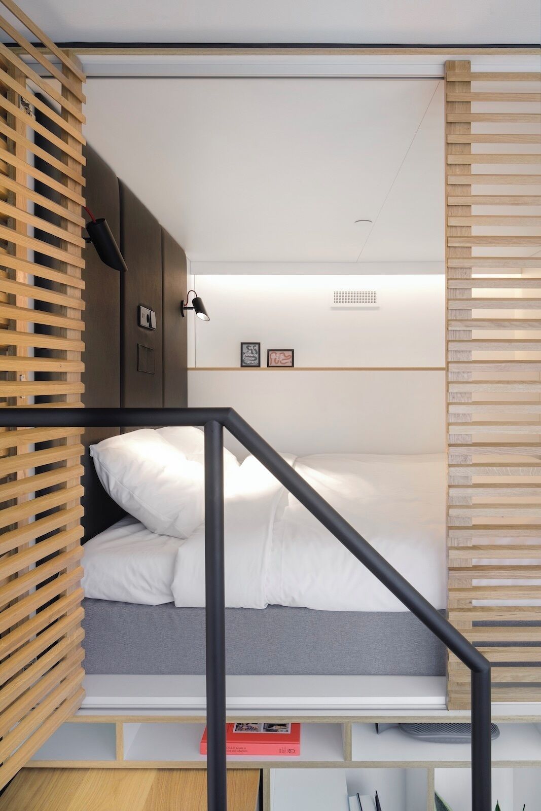 A compact room with a bed, a small desk, and a shelving unit.