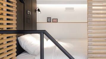 A compact room with a bed, a small desk, and a shelving unit.