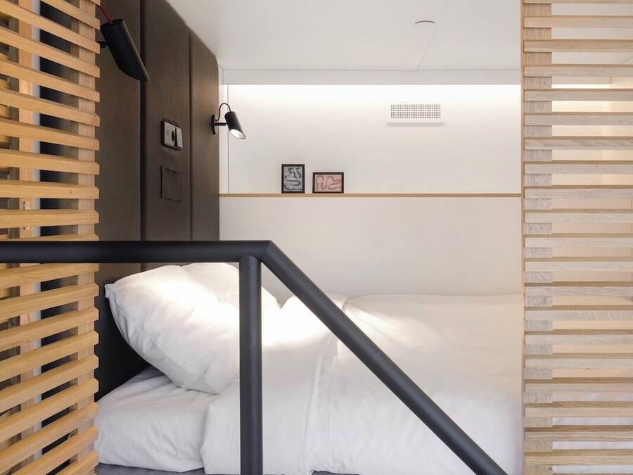 A compact room with a bed, a small desk, and a shelving unit.