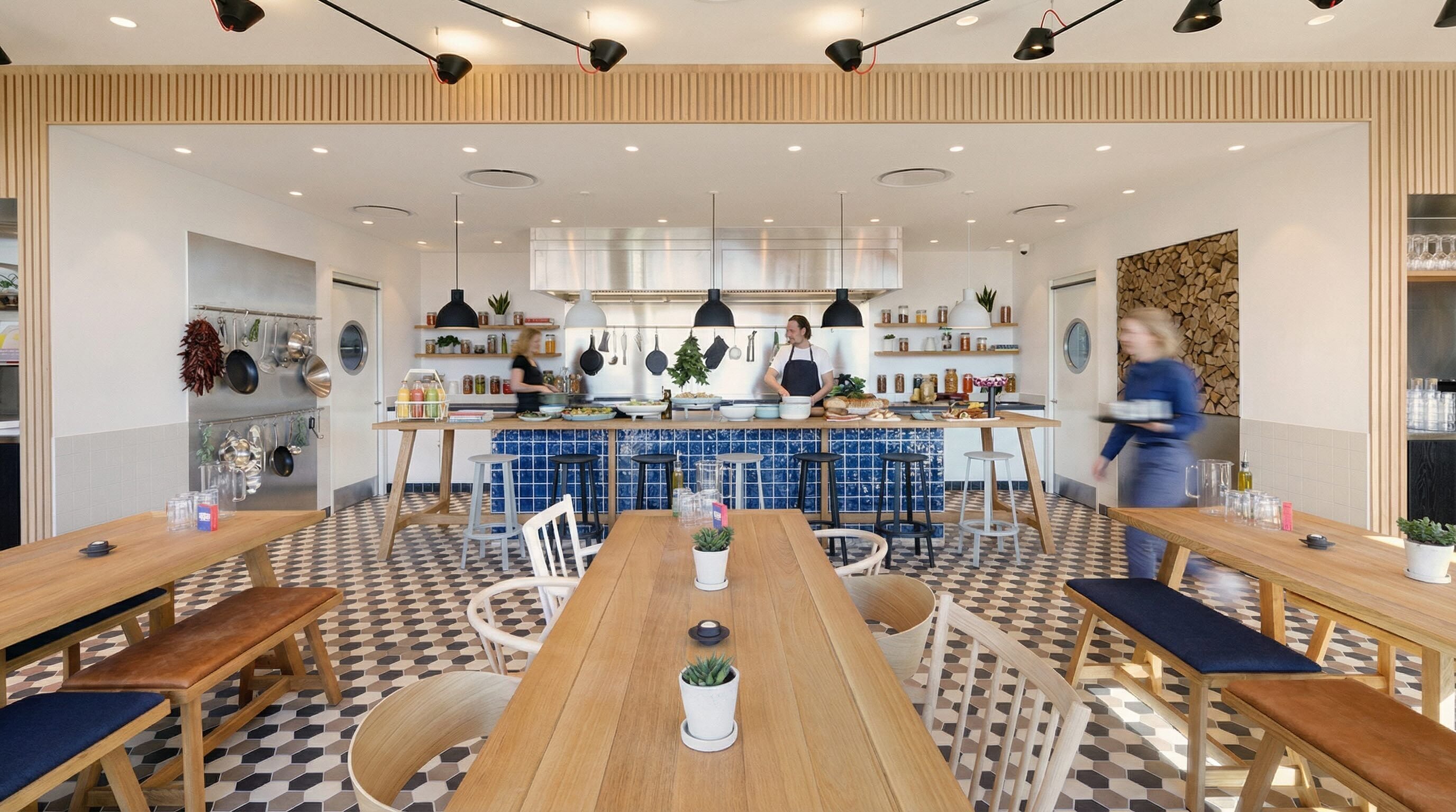 Una cocina moderna con una isla central, mesas y sillas de madera.