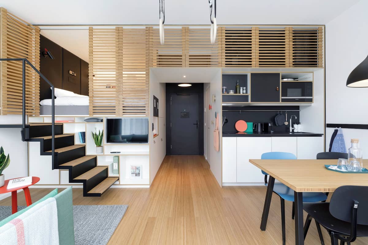 Een modern appartement met keuken, eethoek en een trap naar een slaapkamer op een entresol.