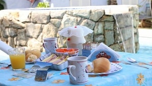A breakfast setup with a stone wall backdrop, featuring a mug, a plate with a bun, and a glass of orange juice. - Pousada Canto Azul (Guarujá)