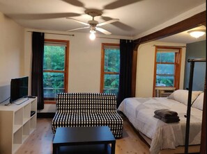 Ein Schlafzimmer mit Bett, einer Couch, einem Fernseher und einem Deckenventilator.