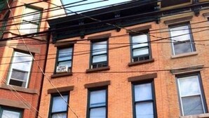 A multi-story brick building with a green door and multiple windows. - Serene Studio close to NYC. Walk to shops, PATH (Jersey City)