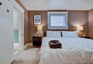 A bedroom with a bed, two bedside tables with lamps, a window with blinds, and a picture on the wall. - Designer House 5BR! Steps to Downtown/Fountain Sq! (Indianapolis)