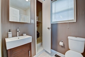 A bathroom with a white sink, a mirror, a toilet, and a shower area. - Designer House 5BR! Steps to Downtown/Fountain Sq! (Indianapolis)