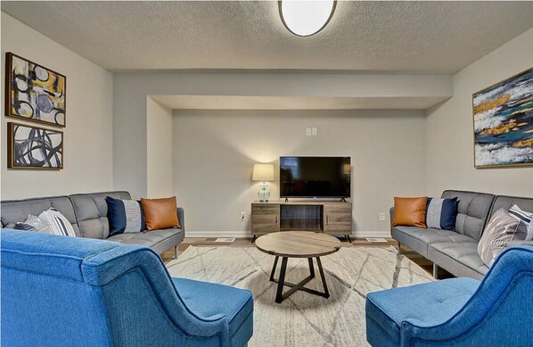 A modern living room with two sofas, a coffee table, and a flat-screen TV.