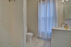 A bathroom with a shower, toilet, and sink.