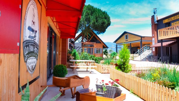 A wooden building with a red awning, a wooden fence, and outdoor seating.