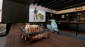 A wooden chess table with a chessboard, a scooter, and a wall with a framed picture.