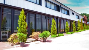A modern building with large windows and a row of potted plants along the walkway.