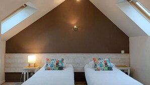 Quarto com duas camas, claraboia e luminária no teto.
