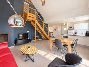 Un espace de vie moderne comprenant un escalier en bois, un coin repas et une cuisine.