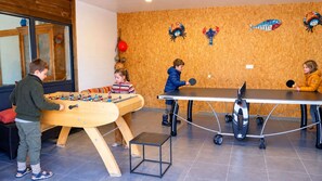 Une pièce équipée d’un baby-foot, d’une table de ping-pong et d’une petite table de tennis de table.