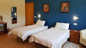 Een slaapkamer met twee bedden, een houten deur, een spiegel en wandlampen.