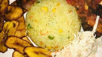 Un plato de arroz, plátanos fritos, un guiso de carne y una ensalada de col.